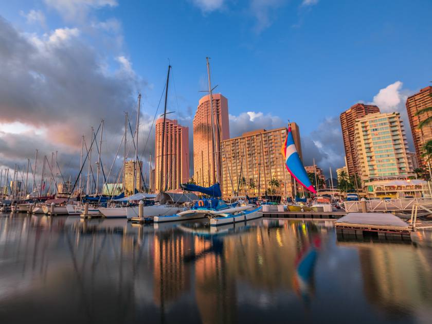 Boats and yachts docked at the Ala Wai Harbor the largest yacht harbor of Hawaii and Honolulu skyline at sunset. On background, a luxurious hotels near Waikiki beach in Honolulu, Oahu, Hawaii.