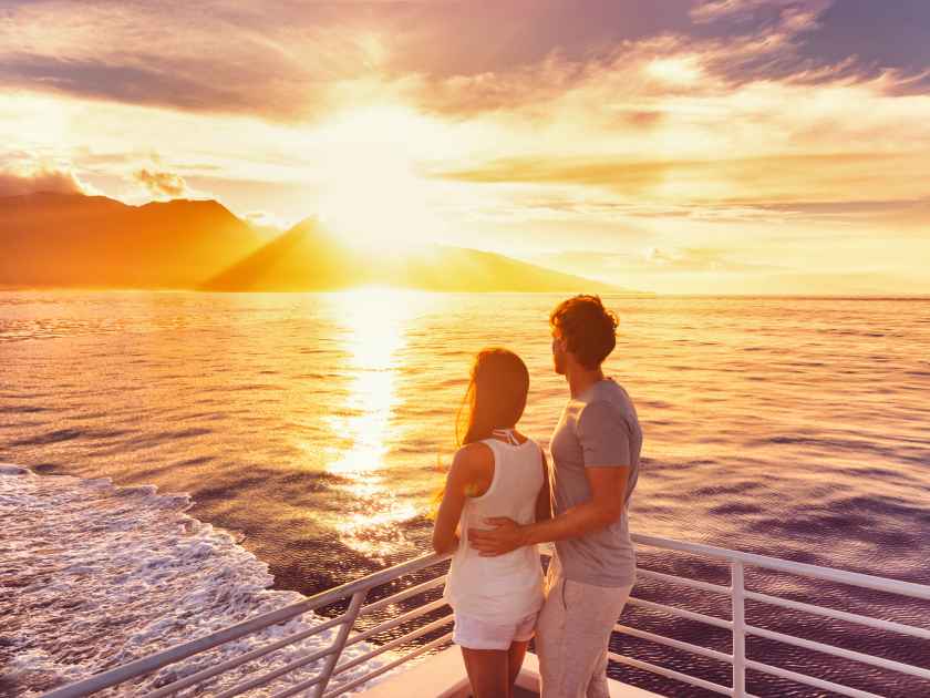 Travel cruise ship couple on sunset cruise in Hawaii holiday. Two tourists lovers on honeymoon travel enjoying summer vacation.