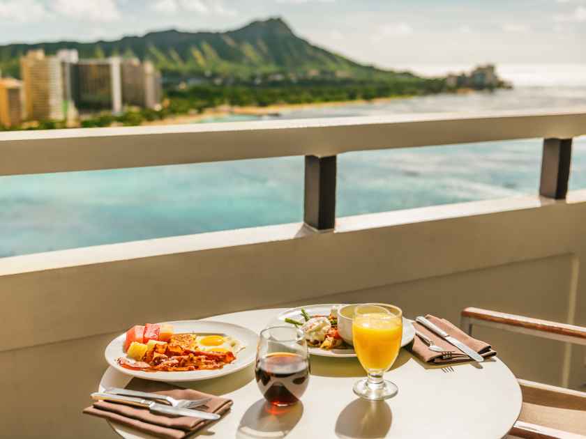 Hotel room breakfast on balcony view of Waikiki beach, Honolulu, Hawaii. Vacation travel morning food American breakfast in luxury resort outside.