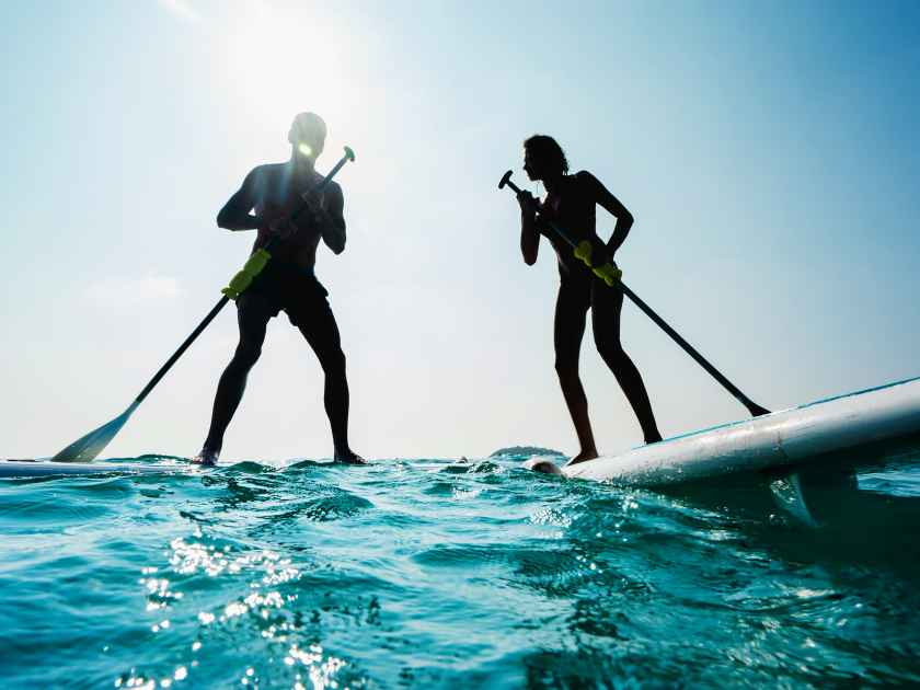 Stand up paddle board couple paddleboarding .Selective focus. People blured with water spray.