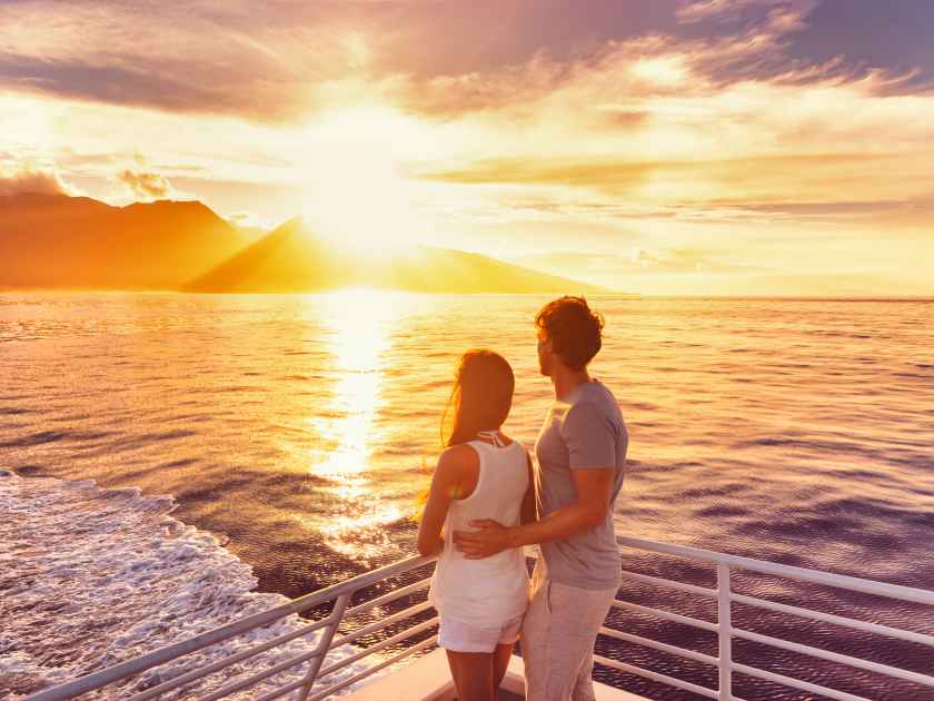 Travel cruise ship couple on sunset cruise in Hawaii holiday. Two tourists lovers on honeymoon travel enjoying summer vacation.