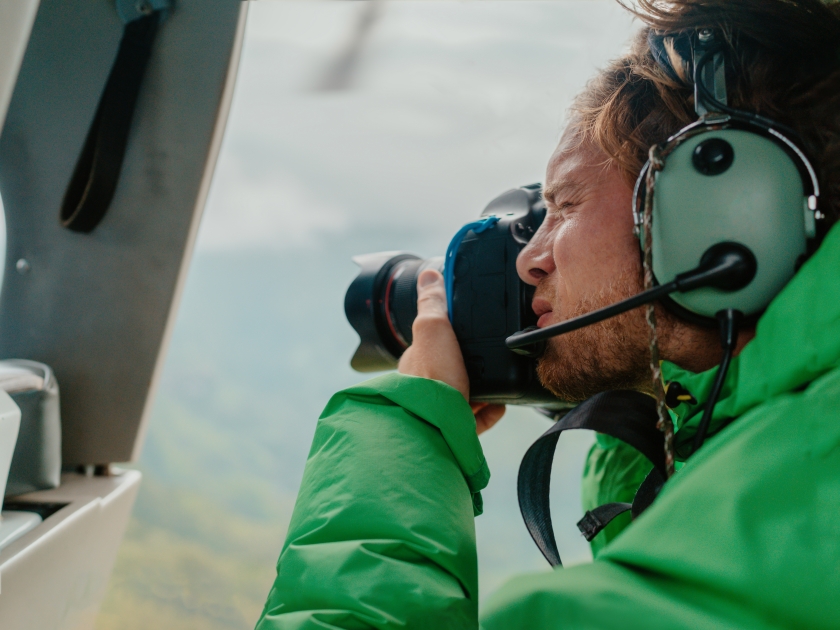 Helicopter doors off ride adventure travel professional man photographer tourist looking at landscape shooting aerial landscape photography with camera in Hawaii.