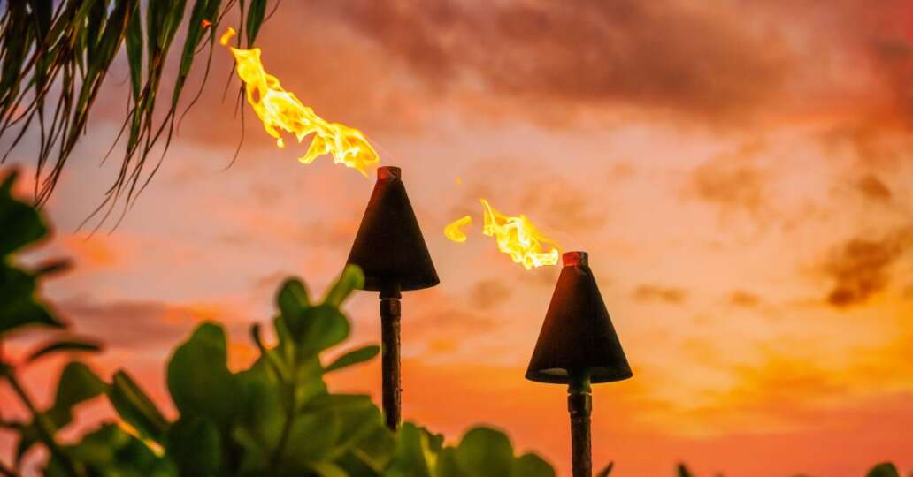 Fire tiki torches against a sunset sky