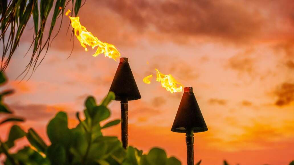 Fire tiki torches against a sunset sky