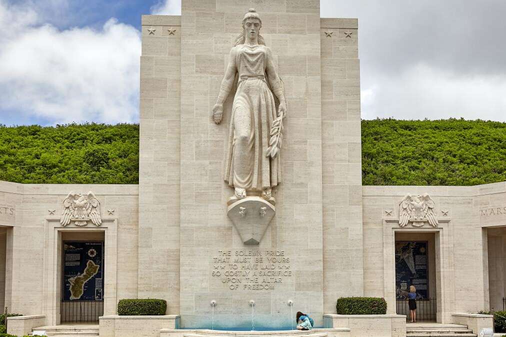 An unidentified woman sits near the fountain monument at National Memorial Cemetery of the Pacific on the island of Oahu, in Hawaii.