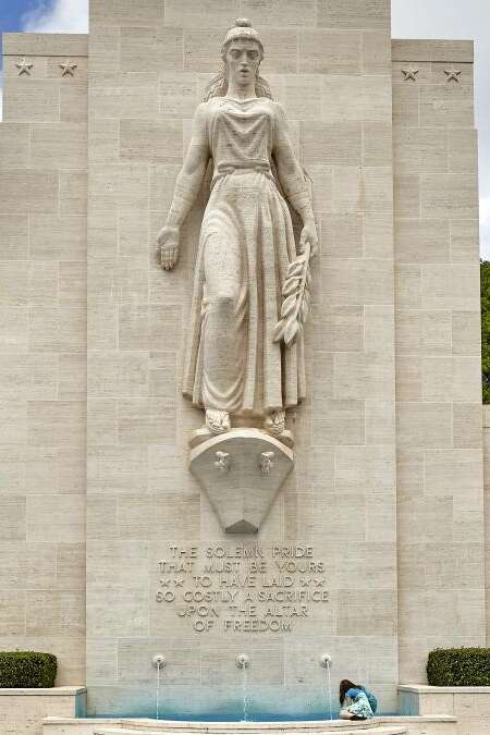 An unidentified woman sits near the fountain monument at National Memorial Cemetery of the Pacific on the island of Oahu, in Hawaii.