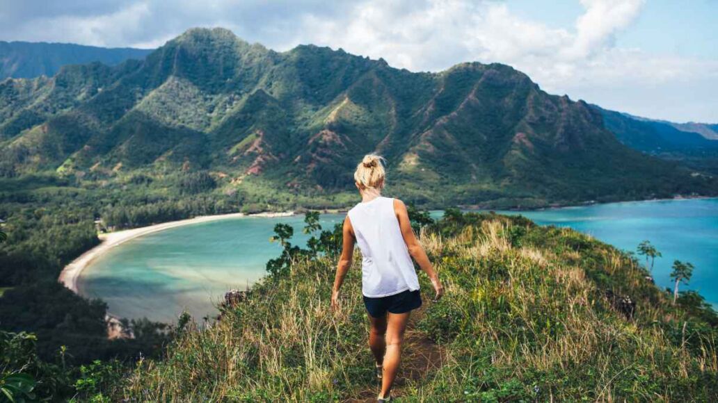 Blonde hiker looks over the ocean on a classic Hawaiian hike.