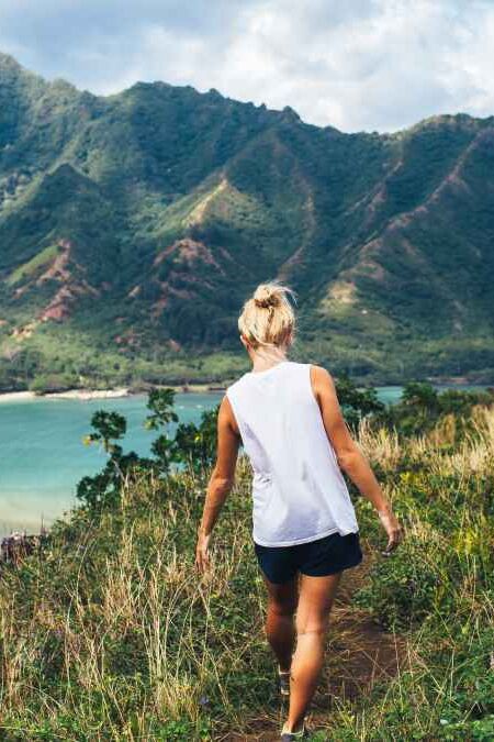 Blonde hiker looks over the ocean on a classic Hawaiian hike.