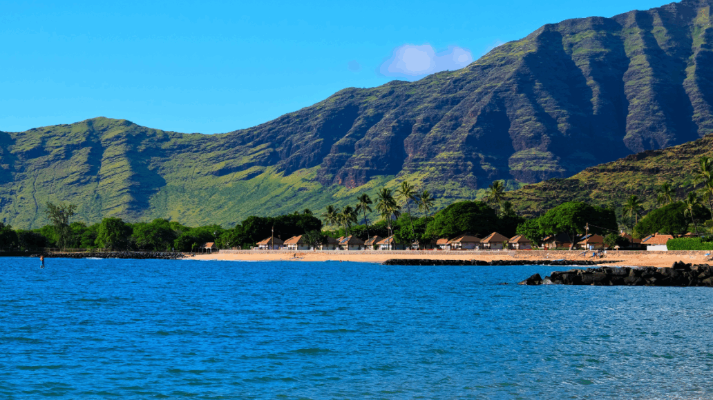 Landscape of the West side of the island of Oahu, Waianae, Hawaii. Pokai Bay beach, coast line, tide pools and Waianae mountain range with palm trees in foreground.