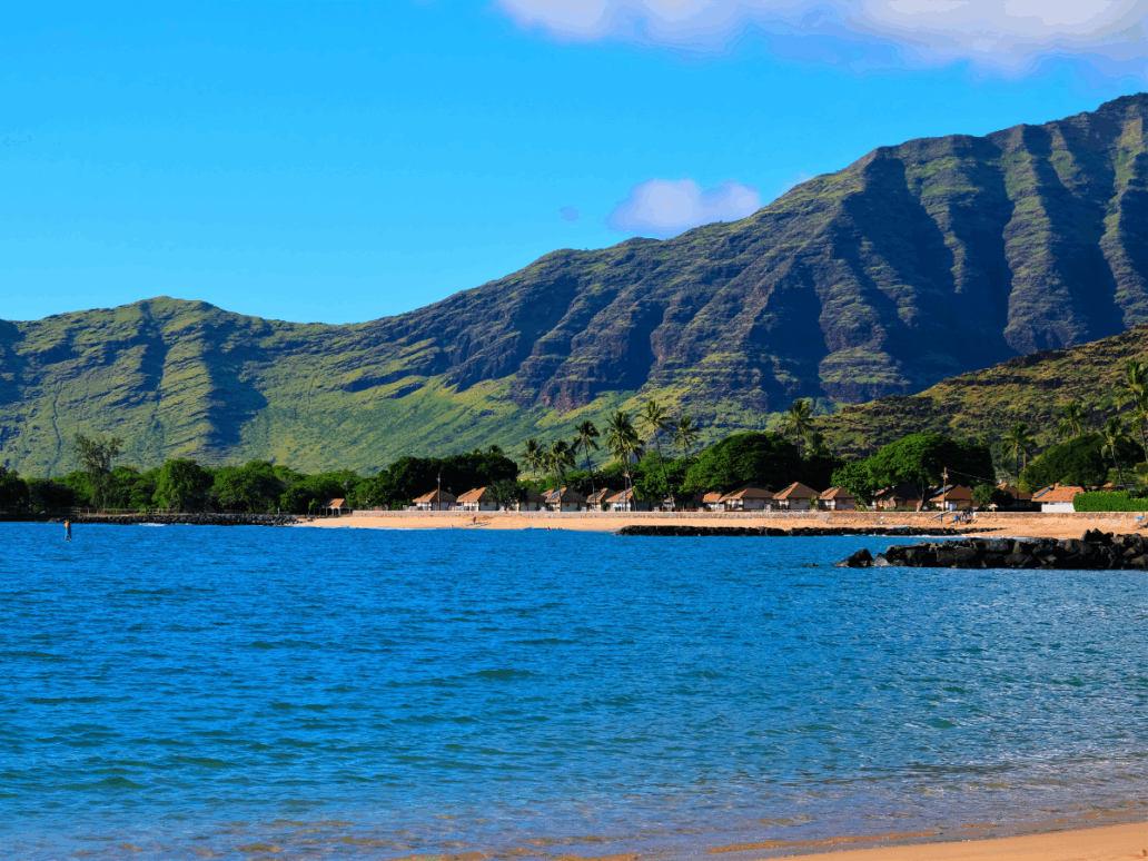 Landscape of the West side of the island of Oahu, Waianae, Hawaii. Pokai Bay beach, coast line, tide pools and Waianae mountain range with palm trees in foreground.