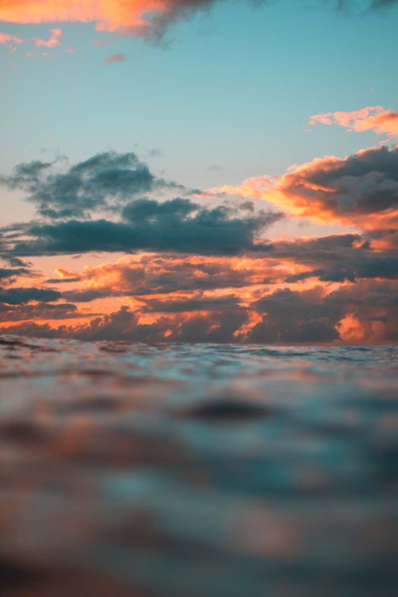 Stunning sunset clouds over the ocean in Waikiki, glowing with orange and pink hues.